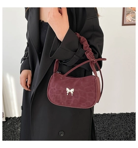Détail du sac hobo bordeaux avec texture animale, fermoir papillon argenté et anse froncée
