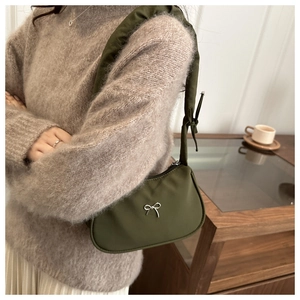 Close-up of olive green dumpling bag with silver bow detail and padded knotted strap