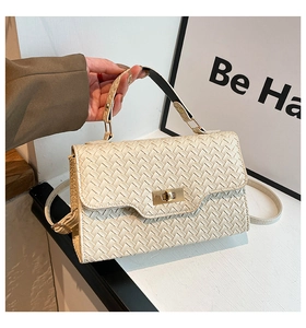 Gros plan du sac bandoulière tissé blanc cassé avec un fermoir doré tournant chic