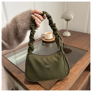 Macro detail of army green pleated handbag with decorative silver metal bow accent