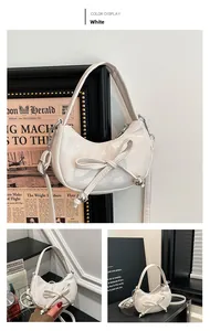 Detail of white glossy mini moon bag with bow decoration and silver bead accents