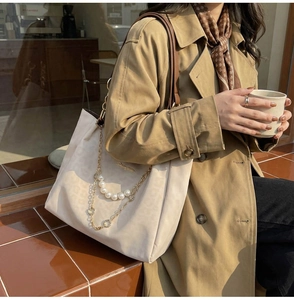 Detail of cream leopard print tote bag with elegant pearl accents and gold chain straps