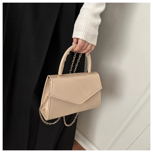 Detail of beige patent leather mini bag with gold chain strap and glossy finish