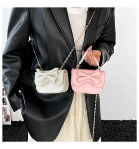Dettaglio della mini borsa alla moda con fiocco, manico di perle e catena d'oro