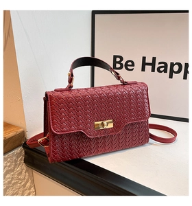 Détail du sac à main tissé bordeaux avec fermoir doré, poignée et bandoulière en cuir