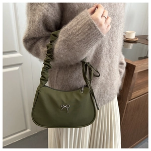 Olive green shoulder bag with silver bow detail and pleated strap worn by a model