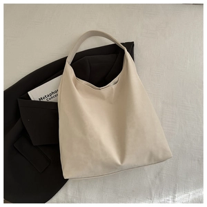 Minimalist beige tote bag shown with black blazer and books in a lifestyle setting