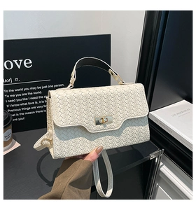 Détail du sac à main tressé crème avec fermoir doré rotatif et texture élégante