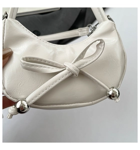 Détail du sac croissant en cuir plissé blanc avec nœud et perles métalliques