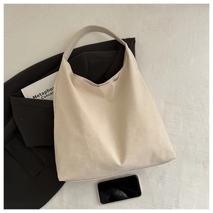 Detail of minimalist beige faux leather tote bag on black blazer for daily commute