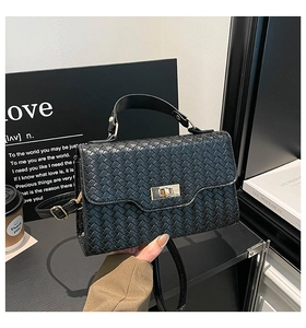 Détail du sac à main tressé noir montrant le fermoir doré et la texture du cuir