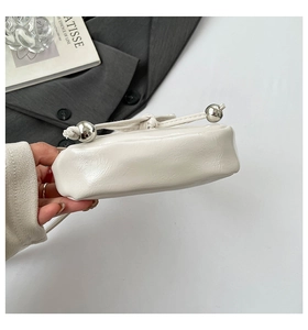 Gros plan du sac plissé blanc montrant les boules métalliques et les détails froissés