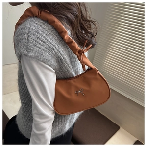 Detailed side view of a brown ruched shoulder bag with a silver metal bow decoration