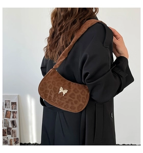 Detail shot of leopard print shoulder bag featuring a gold butterfly buckle on soft strap