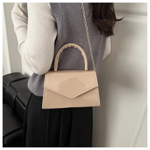 Chic beige patent leather square bag with wavy handle and golden chain strap on model