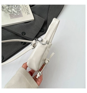 Détail d'un sac en cuir blanc avec perle argentée et décoration de nœud latéral