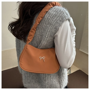 Detail of orange underarm bag with silver butterfly buckle and ruched shoulder strap