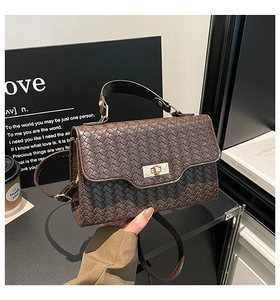 Détail d'un sac à main marron tressé avec fermoir doré et bandoulière réglable