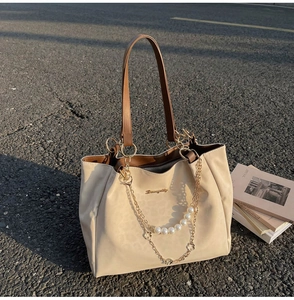 Dettaglio della borsa tote in pelle crema con catena dorata e perle bianche