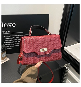 Détail d'un sac à main bordeaux en cuir tressé avec fermoir doré et poignée élégante