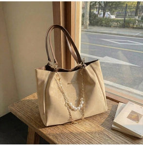 Detail of beige suede tote bag featuring elegant pearl chain and brown handles