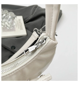 Détail du zip argenté et du cuir crème brillant sur le sac à bandoulière au design moderne