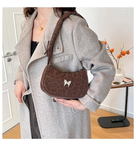 Detail of leopard print shoulder bag featuring a silver butterfly buckle and brown strap