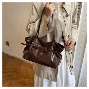 Detailed view of glossy dark brown bucket bag with adjustable straps and silver buckle