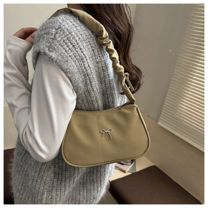Detail of khaki pleated shoulder bag featuring a mini silver metal bow and scrunchie strap