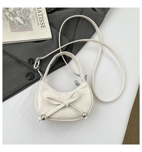 Détail du sac blanc en forme de croissant avec nœud et perles métalliques argentées
