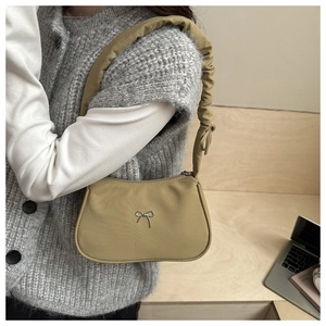Detail of khaki hobo bag with pleated shoulder strap and silver metal bow ornament