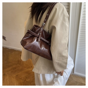 Dettaglio della borsa tote in pelle cerata marrone scuro con occhielli in argento sulla tracolla