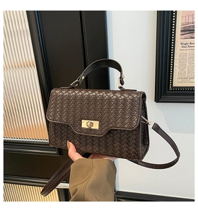 Détail d'un sac à main tissé marron foncé avec fermoir doré et bandoulière réglable