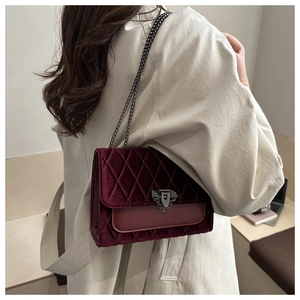 Detail of burgundy velvet quilted bag featuring retro metal chain and elegant lock