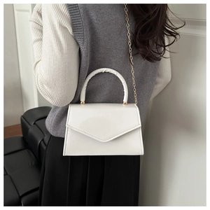 Detail of ivory faux leather handbag featuring a V-shaped flap and ruched top handle