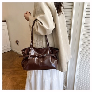 Detail of dark chocolate brown glossy shoulder bag with silver hardware and soft pleats