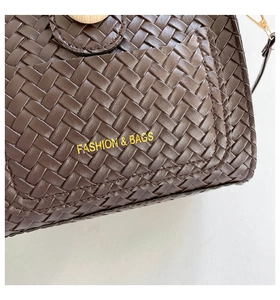 Vue détaillée de la texture en cuir tressé marron foncé et lettrage doré de mode