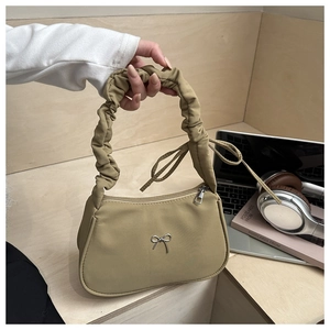Detail of khaki nylon underarm bag with pleated handle and metal bow decoration