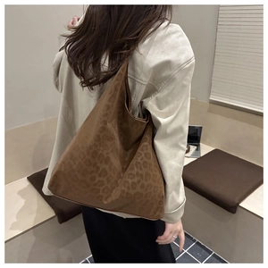 Close-up of a brown leopard print tote bag styled with a beige coat in a cafe setting