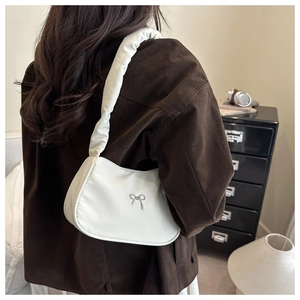 White crescent underarm bag with silver bow detail and pleated strap on model