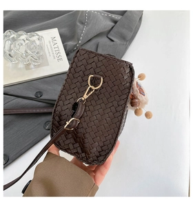 Détail du sac bandoulière tressé marron foncé avec boucles dorées et pendentif peluche