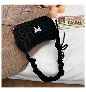 Detail of black leopard print underarm bag with silver butterfly and ruched strap
