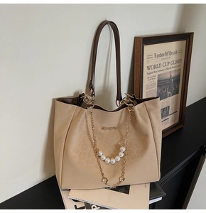 Detail of tote bag with leopard pattern, pearl chain and clover pendant on a desk