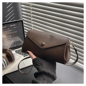 Close-up of brown leather envelope bag with textured finish in a modern lifestyle setting