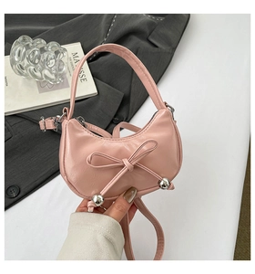 Détail du sac à main rose avec nœud, perles argentées et texture en cuir lisse