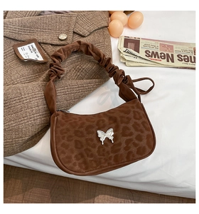 Detail of leopard print underarm bag with silver butterfly charm and pleated handle