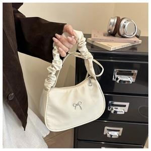 Detail of cream shoulder bag with silver bow accent and pleated scrunchie handle style