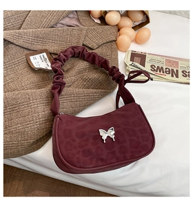 Detail of burgundy shoulder bag with leopard print, butterfly clasp, and ruffled handle