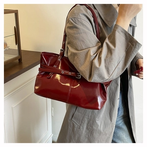 Vista laterale della borsa a secchiello in vernice rosso scuro con fibbia in argento