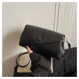 Close-up of minimalist black pebbled leather crossbody bag with flap and magnetic clasp